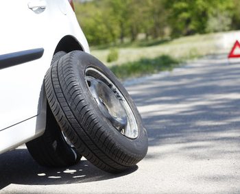 Shot of a car with flat tire problems and a red triangle to warn other road users.