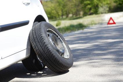 Shot of a car with flat tire problems and a red triangle to warn other road users.