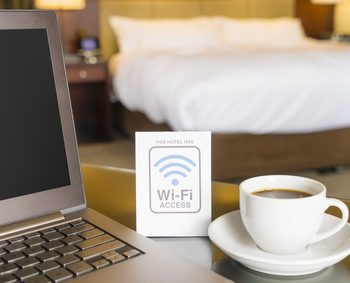 Hotel room with wifi access sign, laptop and cup of coffee