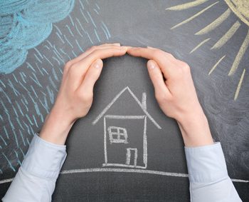 A young businesswoman protects a house from the elements - rain or storm and sun. Blackboard drawing, top view.